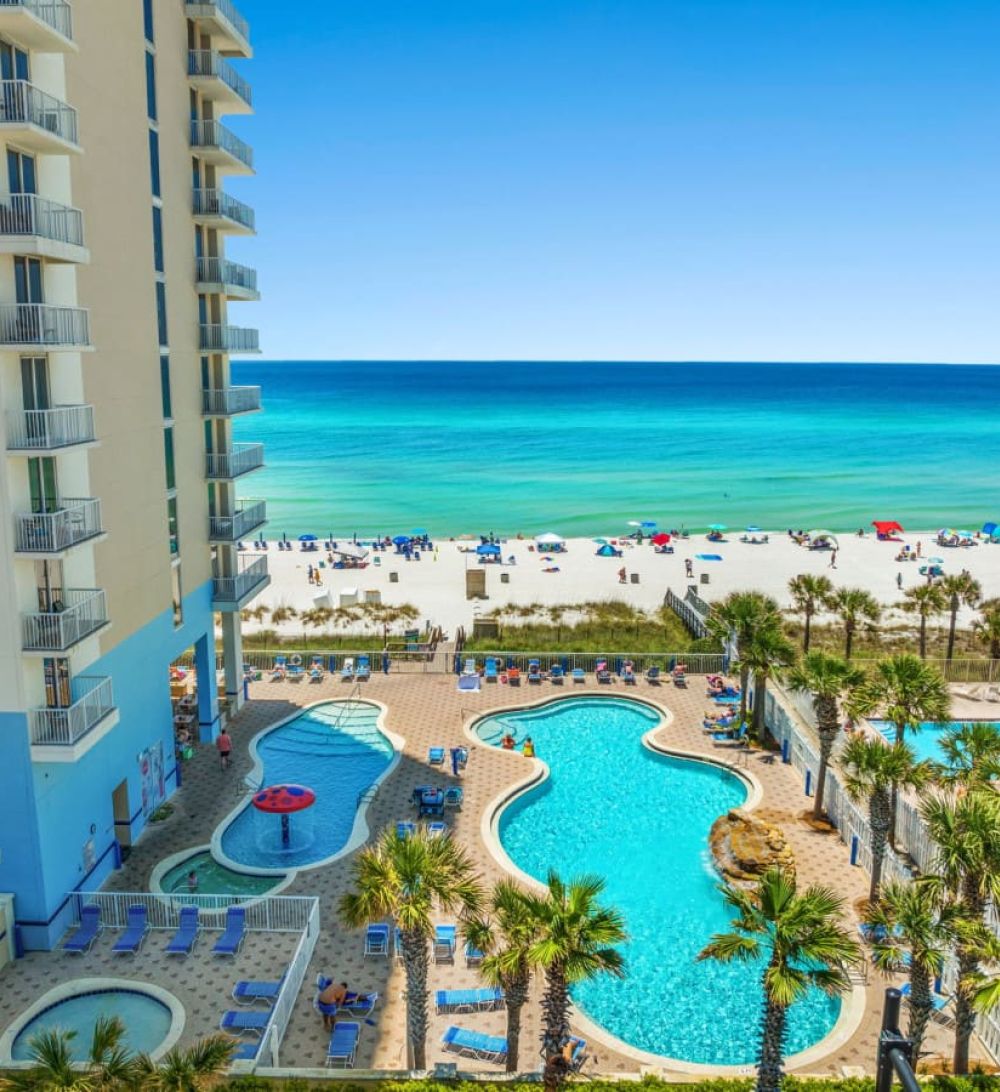 Majestic Beach Resort beachfront pool area with lagoon-style pools, hot tubs, palm trees, and direct access to white sand beaches.