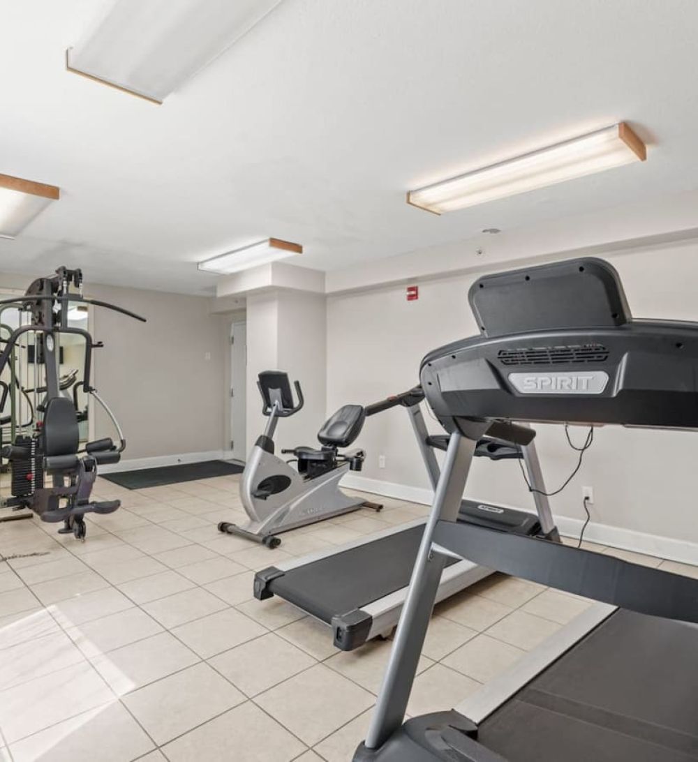 Modern fitness center at Ocean Ritz Resort featuring treadmills, strength machines, and bright workout space.