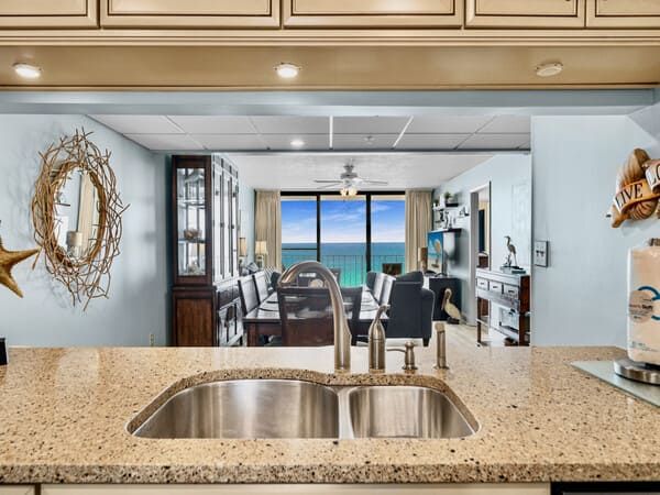 View from the kitchen of an Edgewater Beach Resort condo overlooking the living room and large windows framing the Gulf of Mexico.