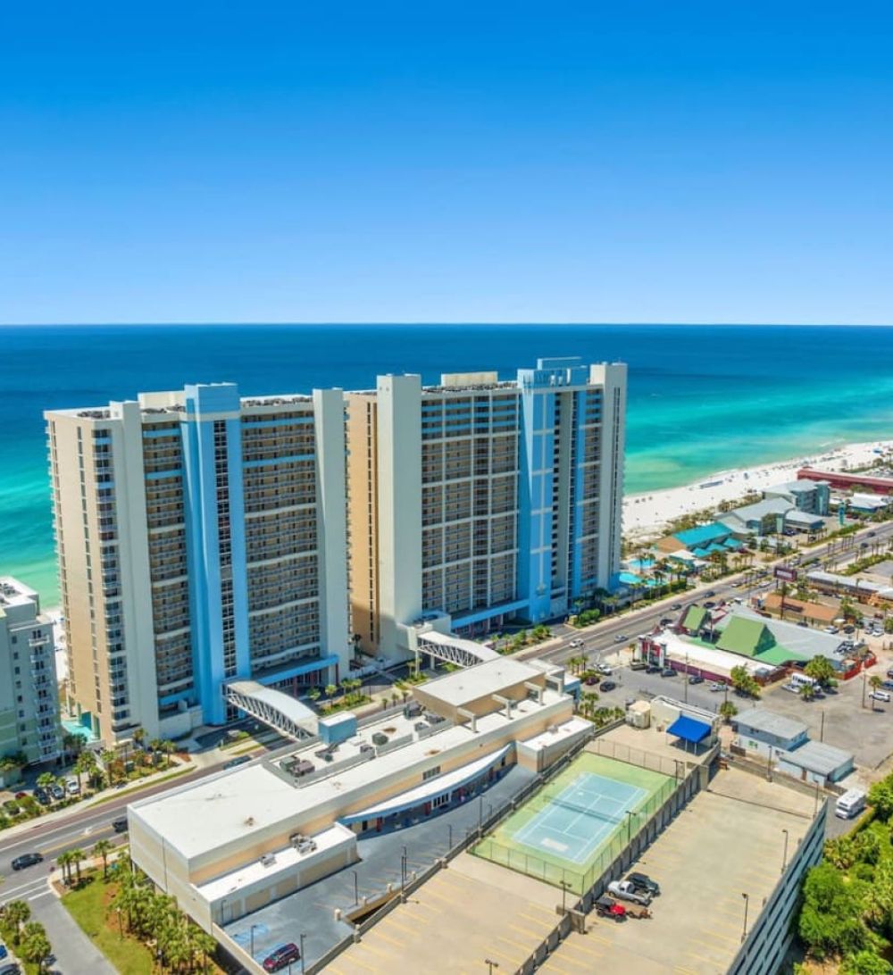 Aerial view of Majestic Beach Resort in Panama City Beach showcasing beachfront towers, turquoise water, and nearby attractions.