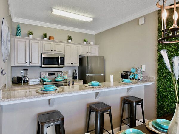 Modern kitchen with stainless appliances, bar seating, and coastal décor inside an Ocean Ritz condo.