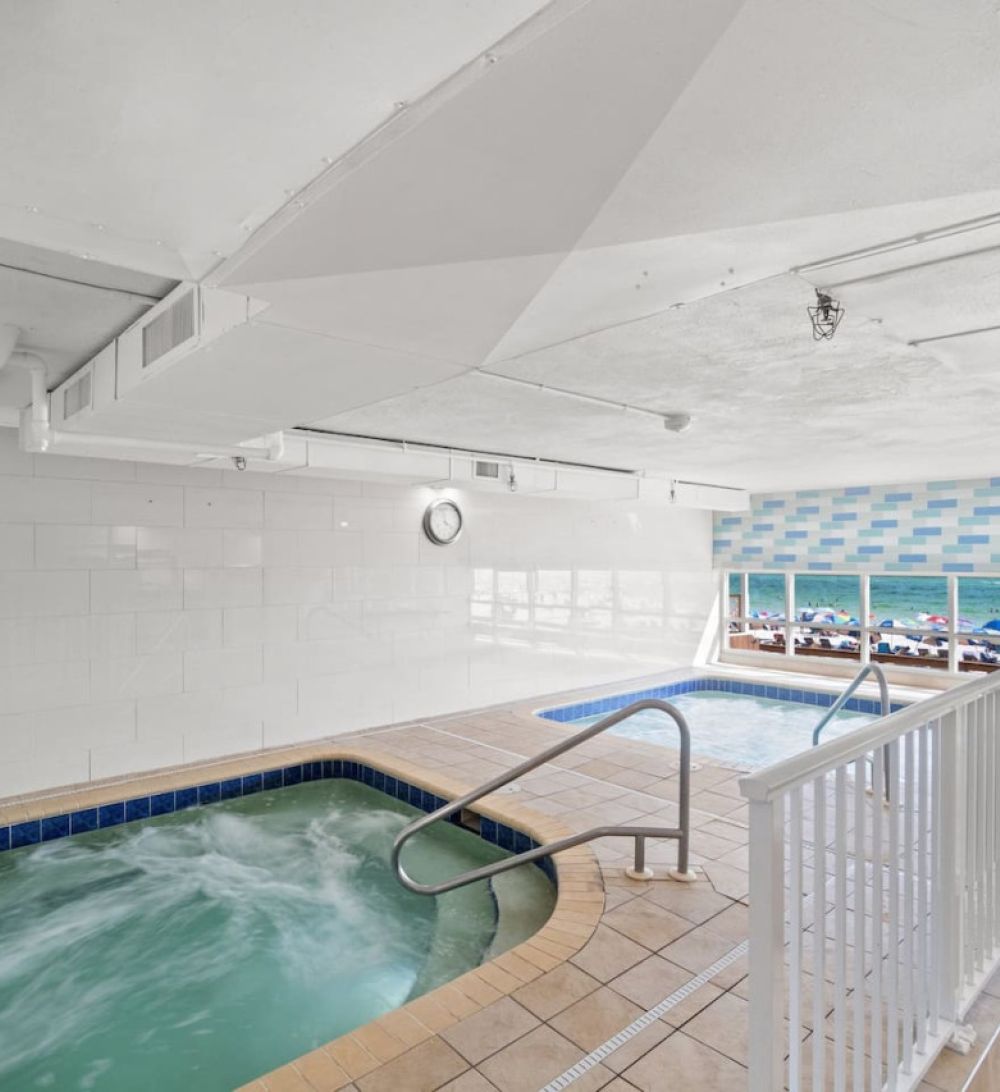 Indoor Roman spa and heated pool at Tidewater Beach Resort overlooking the Gulf of Mexico through large picture windows.