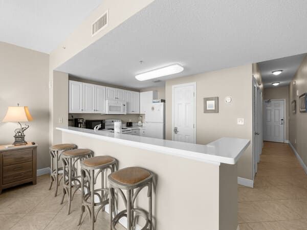 Condo kitchen with breakfast bar, white cabinetry, and modern appliances at Majestic Beach Resort.