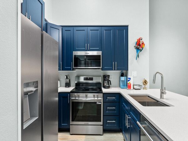 Fully equipped kitchen at a Tidewater Beach Resort condo with stainless steel appliances, blue cabinetry, and modern finishes.