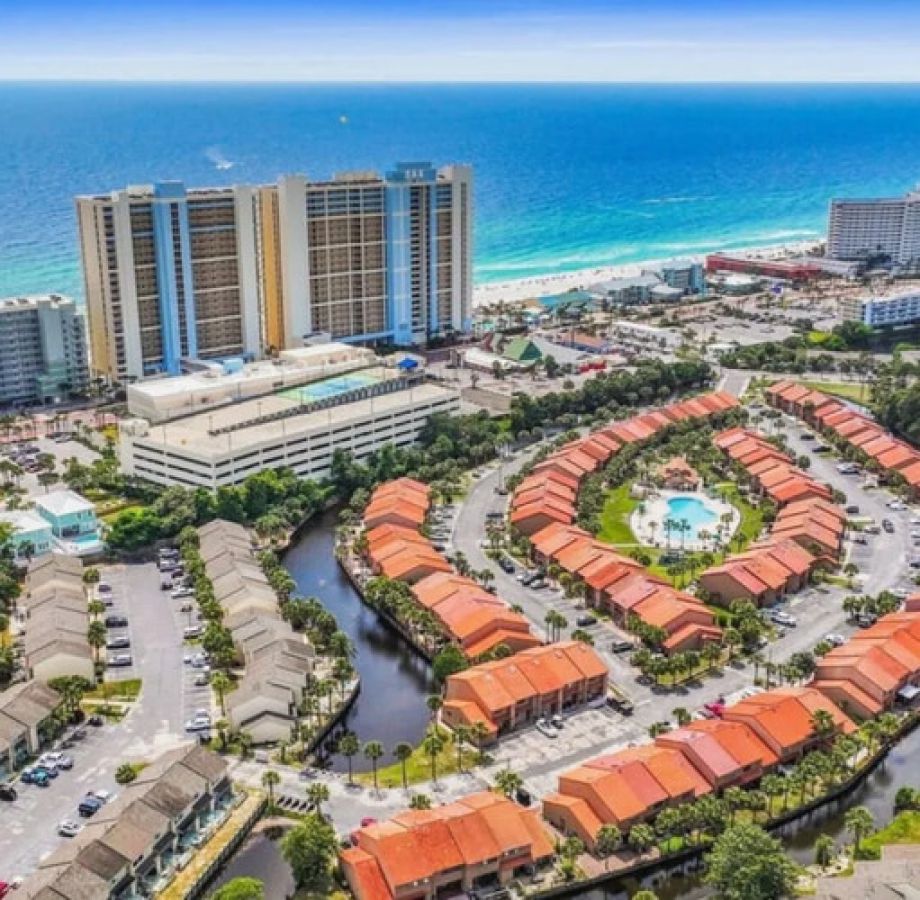 Drone view of Gulf Highlands Beach Resort showing the townhouse community layout, central pool, and nearby beachfront towers.