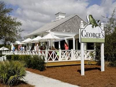 Charming streets of Rosemary Beach town center with shops, balconies, and people walking along 30A.