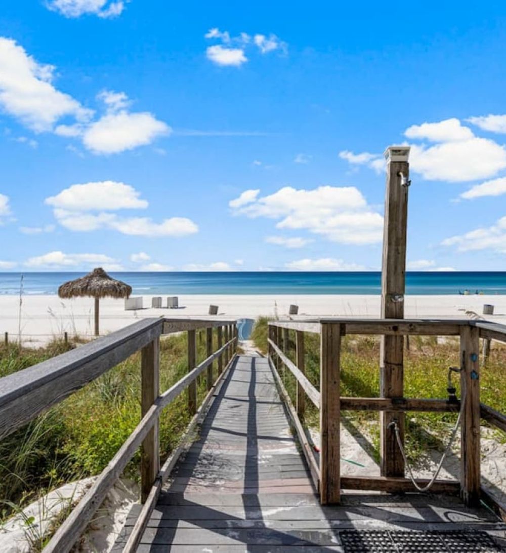 Wooden boardwalk leading to the white-sand beach and emerald Gulf waters at Grandview East Resort.