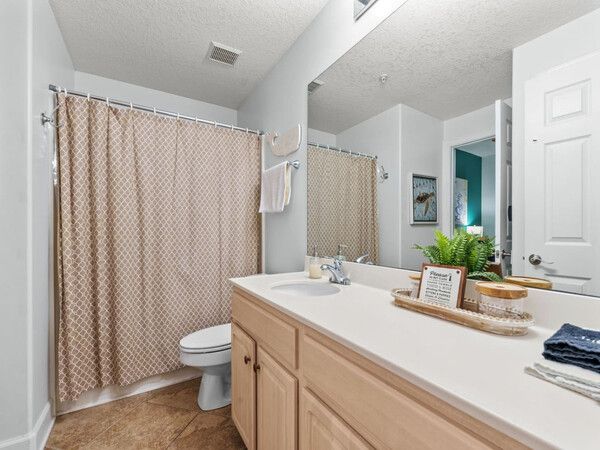 Clean and bright bathroom with large vanity, shower-tub combo, and neutral beach-inspired décor.