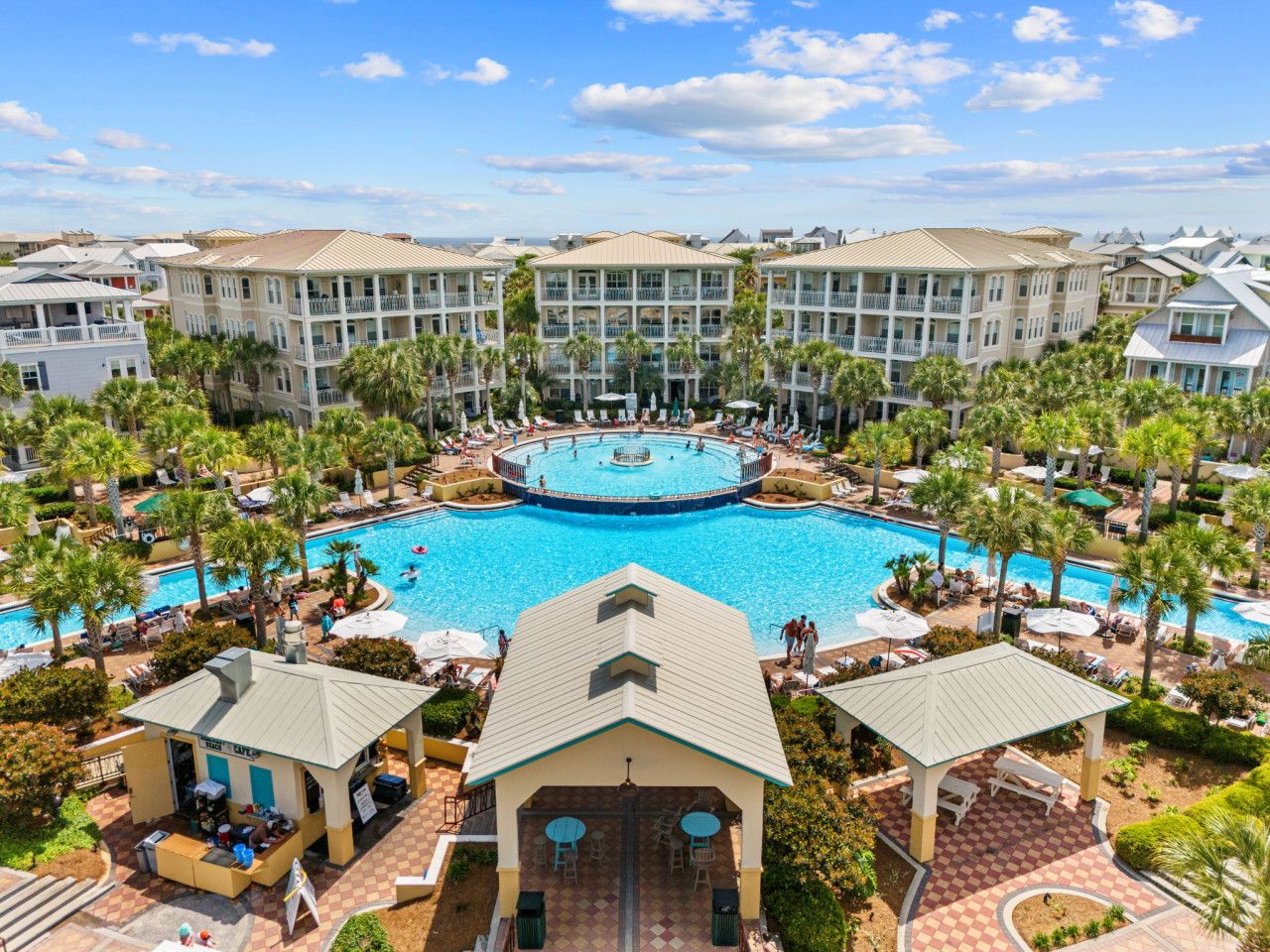 Aerial view of Seacrest Beach’s iconic 12,000-square-foot lagoon pool surrounded by palm trees, lounge chairs, and resort-style buildings.