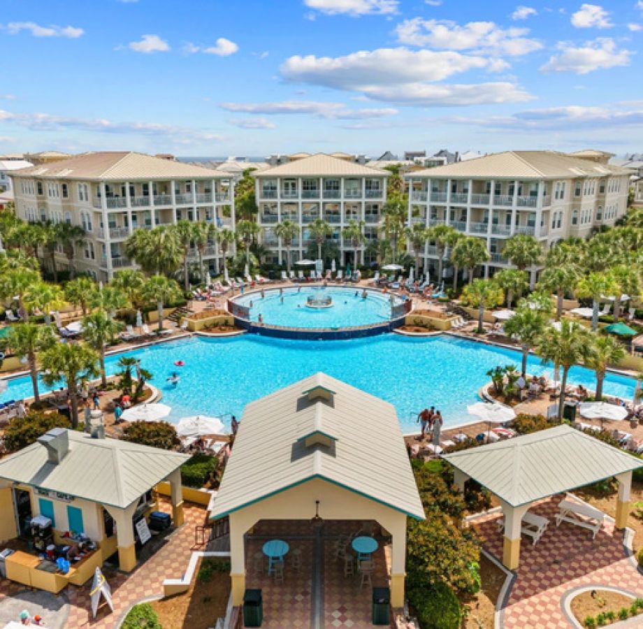 Aerial view of Seacrest Beach’s iconic 12,000-square-foot lagoon pool surrounded by palm trees, lounge chairs, and resort-style buildings.