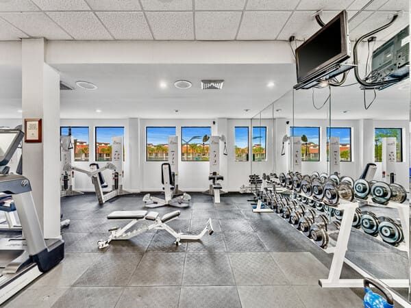 Edgewater Beach Resort fitness center with strength machines, free weights, cardio equipment, and large windows overlooking the property.