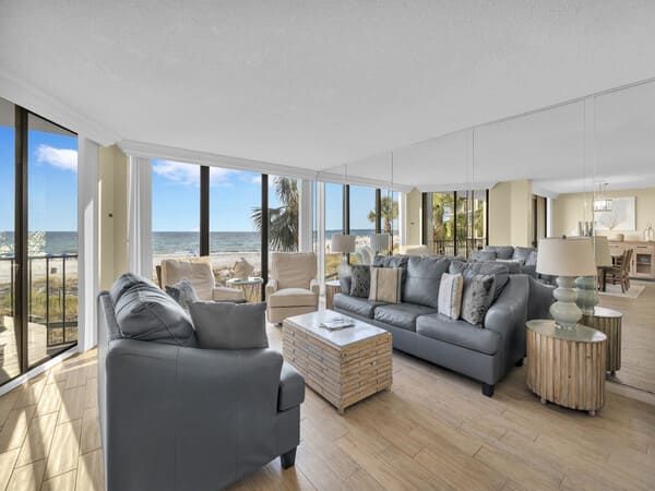 Gulf-front living room at Edgewater Beach Resort with large windows, coastal furniture, and direct views of the Gulf of Mexico.