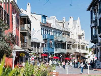 Charming streets of Rosemary Beach town center with shops, balconies, and people walking along 30A.