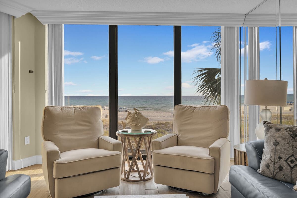Cozy sitting area with two armchairs overlooking the Gulf of Mexico through expansive windows inside a beachfront condo at Edgewater Beach Resort in Panama City Beach, FL.