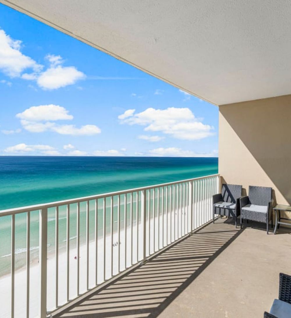Spacious Gulf-front balcony at Grandview East Resort featuring outdoor seating and sweeping views of emerald waters and white-sand beaches.