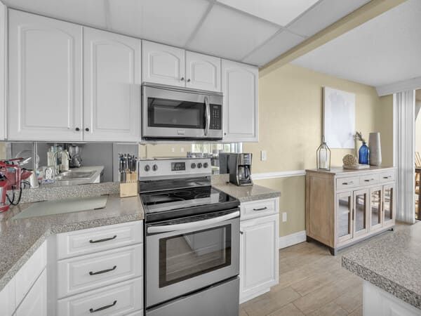 Fully equipped condo kitchen at Edgewater Beach Resort featuring modern appliances, white cabinetry, and spacious countertops.