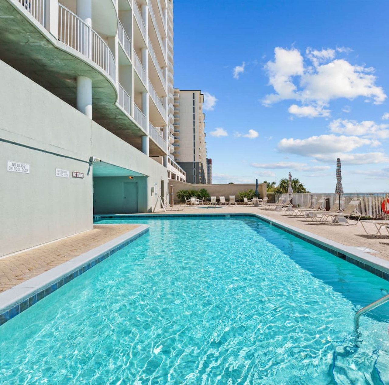 Beachfront pool at Ocean Ritz Resort with lounge chairs and ocean views on a sunny day.