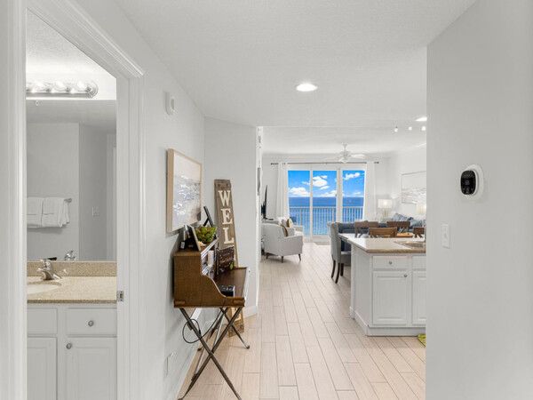 Open-concept living area and kitchen at Grandview East Resort Condo with coastal décor, dining space, and direct views of the Gulf from the balcony.