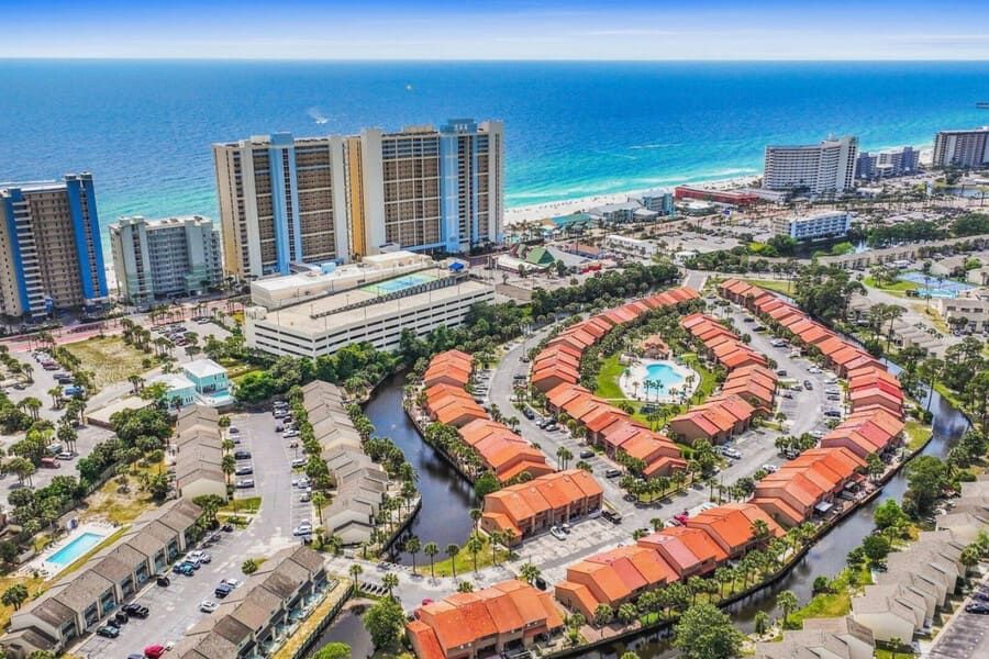 Drone view of Gulf Highlands Beach Resort showing the townhouse community layout, central pool, and nearby beachfront towers.