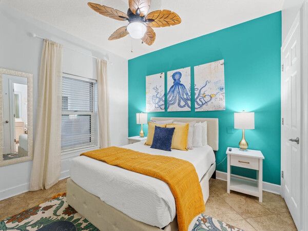 Bright coastal bedroom with teal accent wall, octopus artwork, and cozy queen bed at Ocean Ritz Resort.