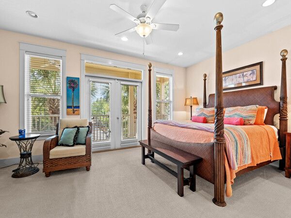 Spacious primary bedroom with four-poster bed, tropical décor, and private balcony access in Seacrest Beach home.