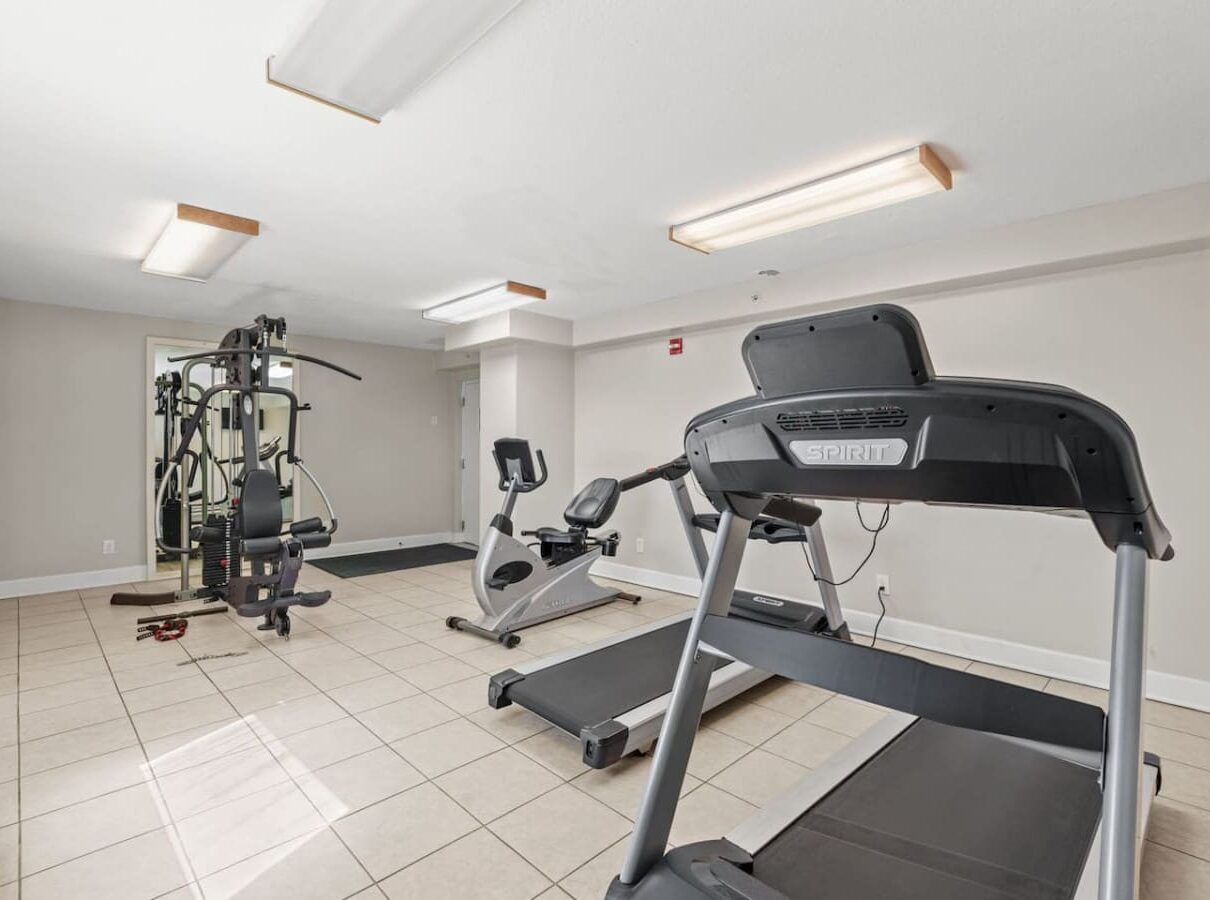 Modern fitness center at Ocean Ritz Resort featuring treadmills, strength machines, and bright workout space.