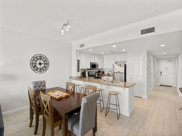 Open-concept dining and kitchen area with seating for six in the Grandview East beachfront condo.