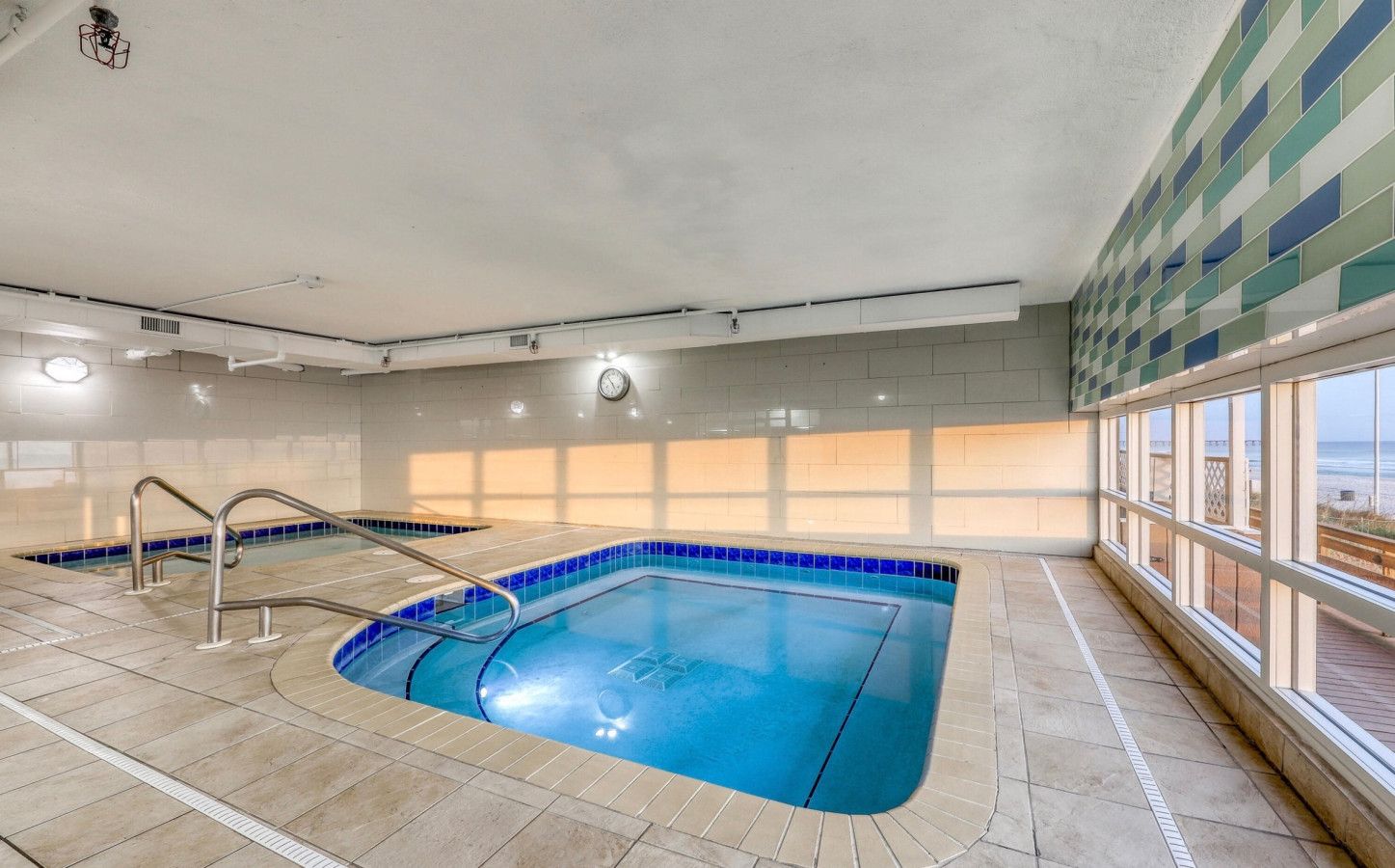 Indoor Roman spa and heated pool area at Tidewater Beach Resort with Gulf views through large windows.