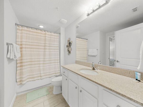 Bright guest bathroom with a large vanity, granite countertop, and tub-shower combo at Grandview East.