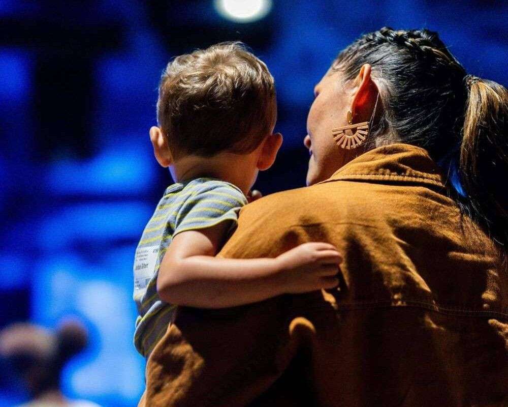 A mother carrying her son before entering a game.