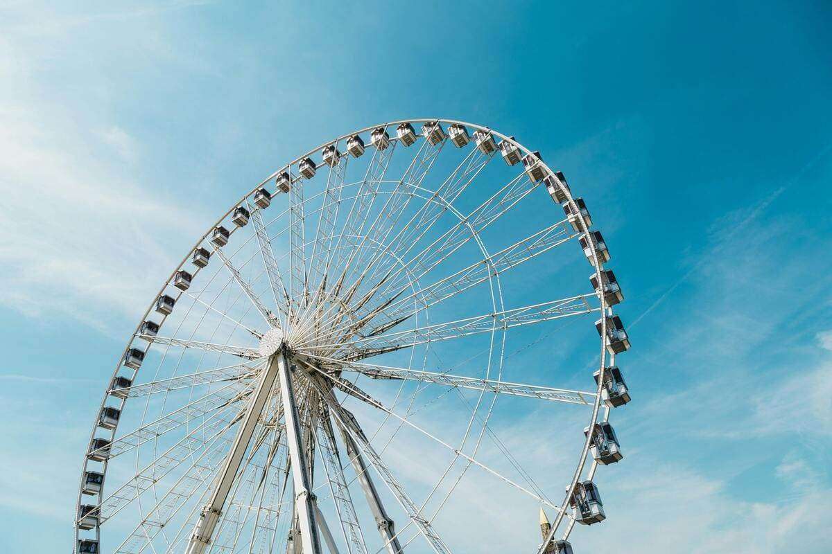 A low-angle photograph of a large Ferris wheel against a bright blue sky.