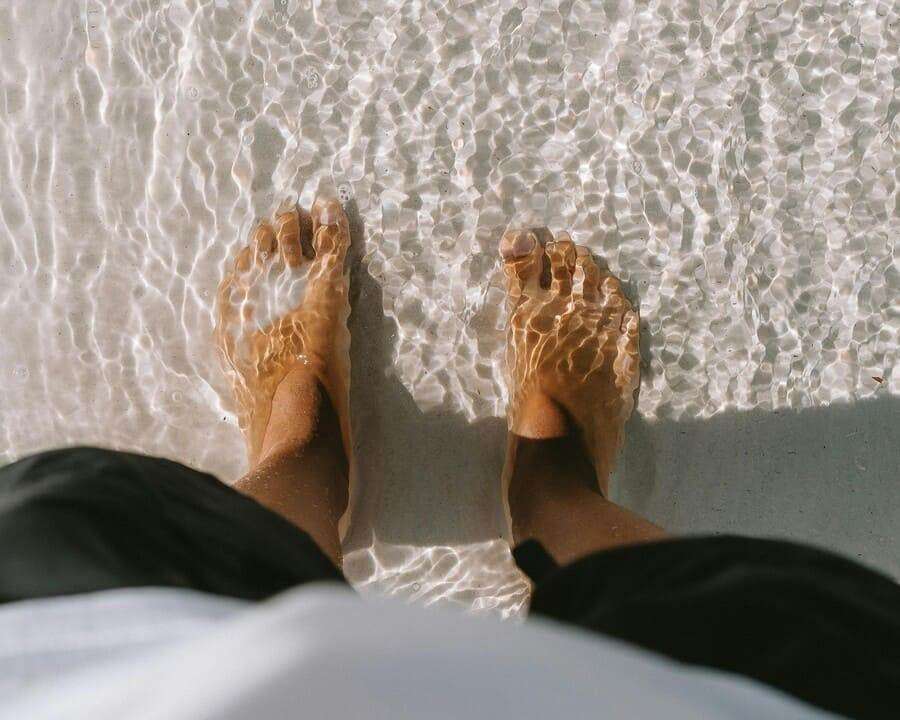 Experience tranquility with bare feet in clear water and white sand