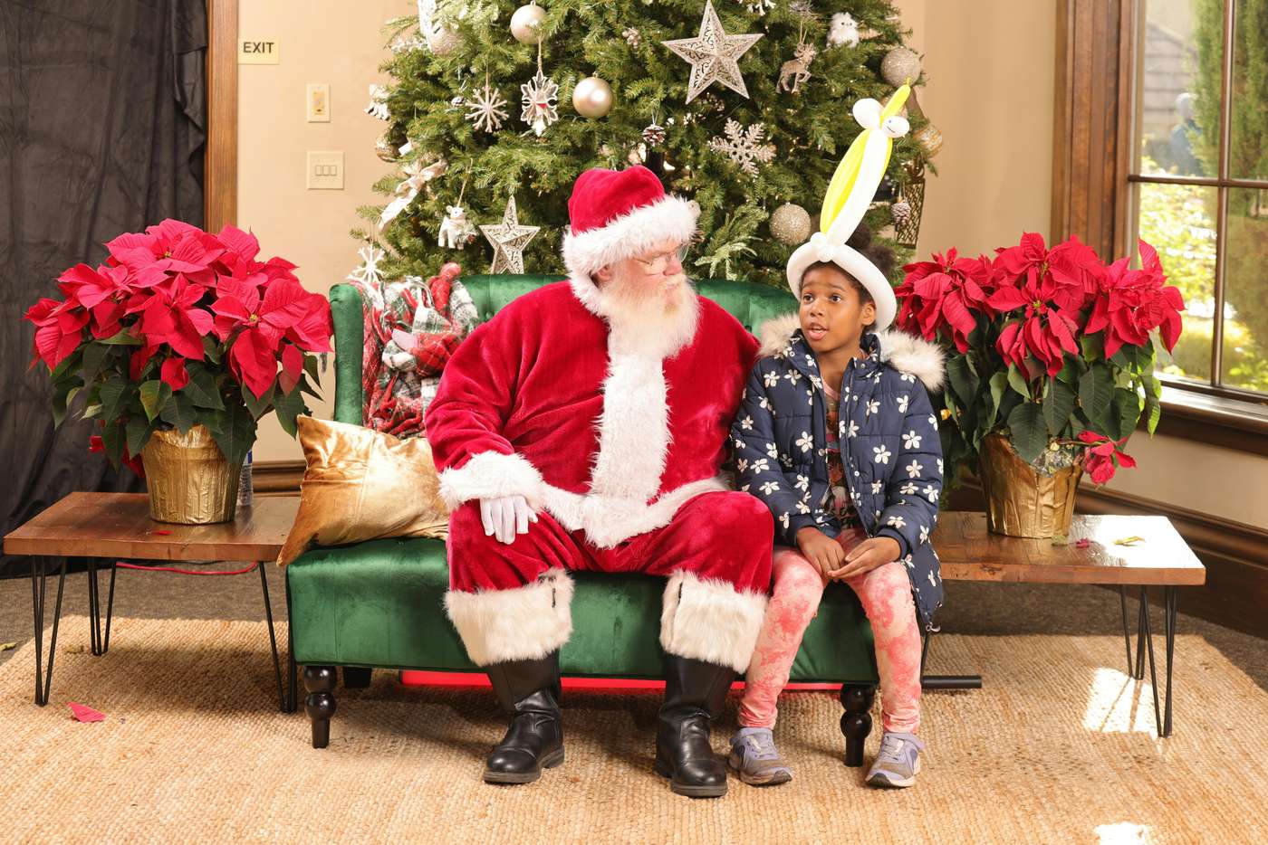 A joyful scene of a child with Santa Claus by a decorated Christmas tree indoors.