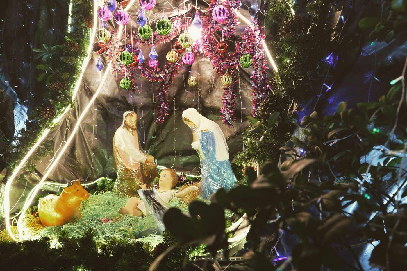 A festive nativity scene with colorful Christmas decorations and lights.