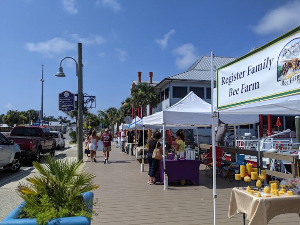 Outdoor waterfront weekend farmers market with leashed dogs and local vendors near Panama City Beach